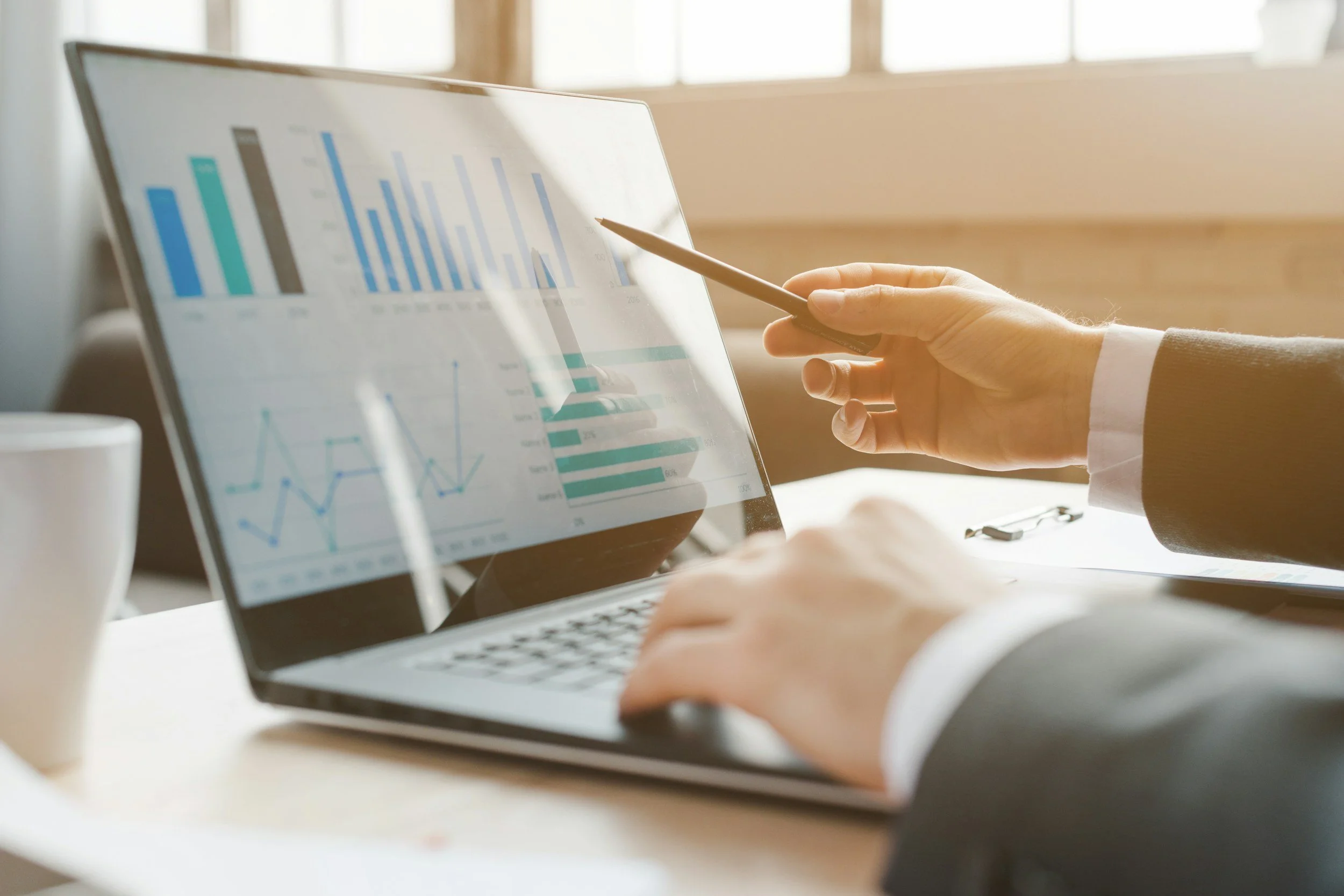 Hands pointing to financial charts on a laptop